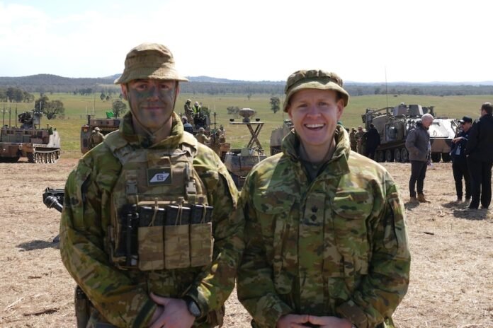 Two smiling soldiers in camouflage clothing.