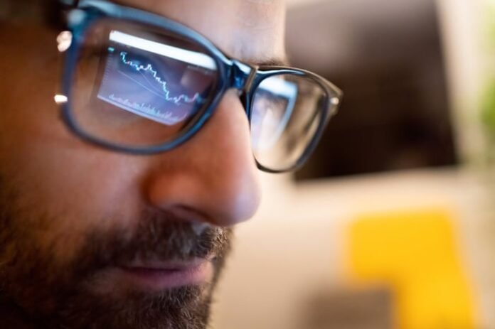 A stock chart from a computer monitor reflected in the glasses of a professional money manager. 