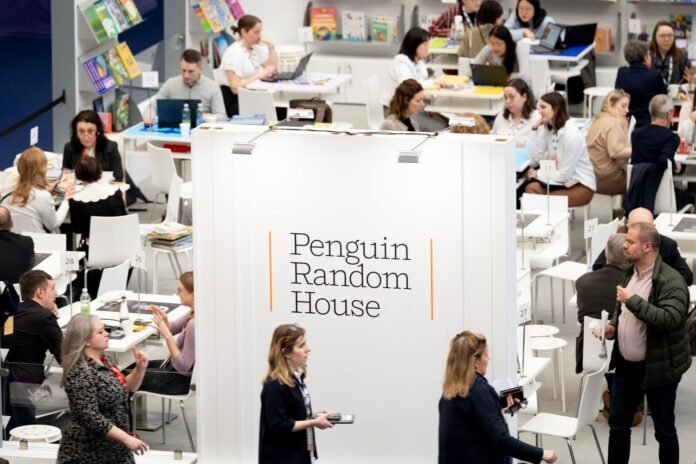 A room full of people at tables surrounding a large sign reading 'Penguin Random House'