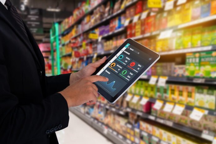 iot smart retail in the futuristic concept, the retailer holds the tablet and uses augmented reality technology to monitor data of off-shelf, price, planogram, compliance campaign in real time