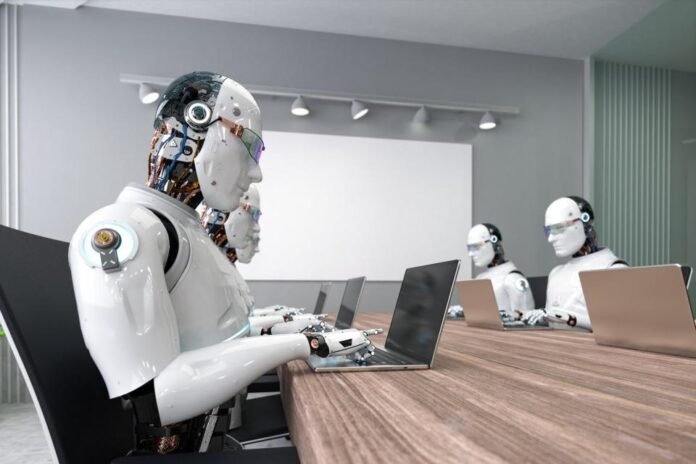 Multiple humanoid robots type on laptops while sitting at a long table in an office conference room. 