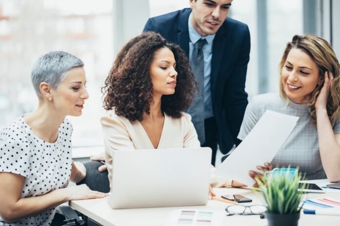 A group of investors gather around a table to study something.