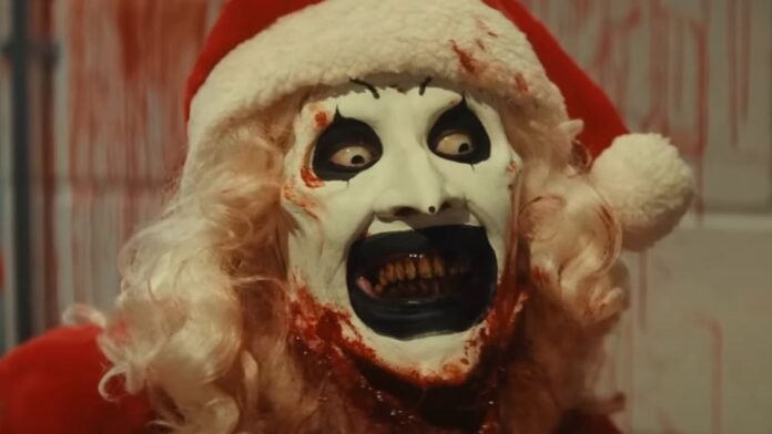 David Howard Thornton as Art the Clown wearing a Santa costume with his face covered in blood in Terrifier 3.