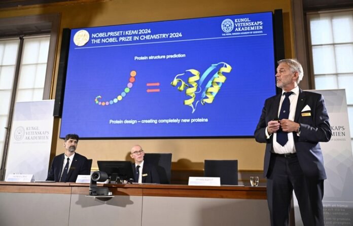 Johan Åqvist, right, member of the Nobel Committee for Chemistry, explains the work of David Baker, Demis Hassabis and John M Jumper, winners of this year's Nobel Prize in Chemistry at the Royal Swedish Academy of Sciences.